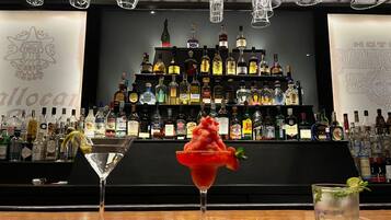 Een bar met een divers assortiment drankflessen en twee bijzondere cocktails.