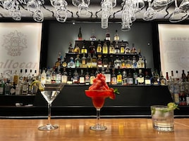 A bar area with a variety of liquor bottles and two unique cocktails.