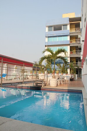 A swimming pool with lounge chairs and a palm tree, surrounded by a building with multiple balconies. - Grand Hotel Plaza Veracruz (Veracruz)
