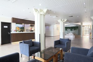 A lobby with a reception desk, seating area, and a staircase leading to another level. - Hotel D. Luís (Coimbra)