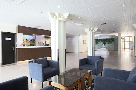 A lobby with a reception desk, seating area, and a staircase leading to another level.. Hotel D. Luís