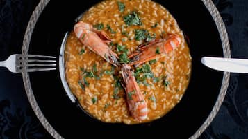 Un plat de fruits de mer, avec des crevettes, servi dans une assiette noire, accompagné d’une fourchette et d’une cuillère.