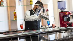 A bar area with a bartender preparing drinks, glasses on the counter, and a coffee machine. - Parador (ZACATECAS)