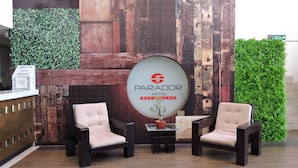 A reception area with a wooden wall, two chairs, a small table with a plant, and a sign for 'PARADOR HOTEL ZACATECAS'. - Parador (ZACATECAS)