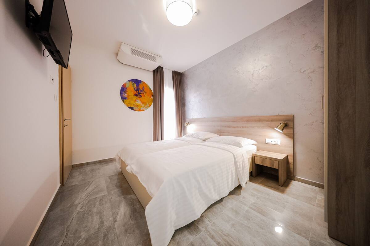 Un dormitorio moderno con cama, mesita de noche y televisor montado en la pared.