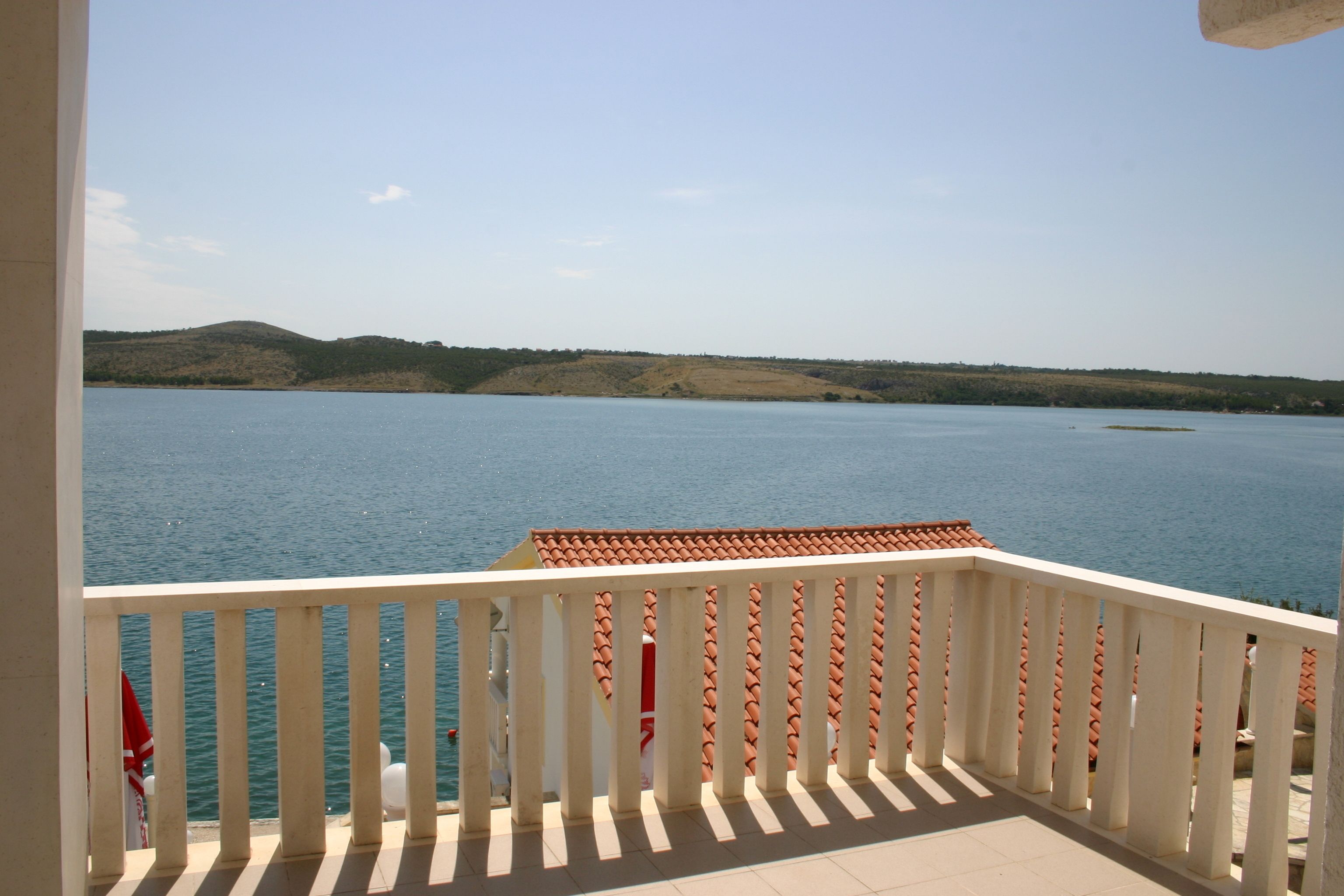 Un balcon donnant sur un lac paisible et des collines lointaines.