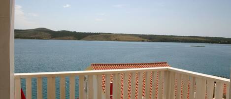 Un balcon donnant sur un lac paisible et des collines lointaines.