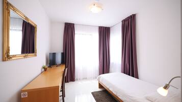 Une chambre d’hôtel avec un lit, un bureau, une télévision et un miroir.