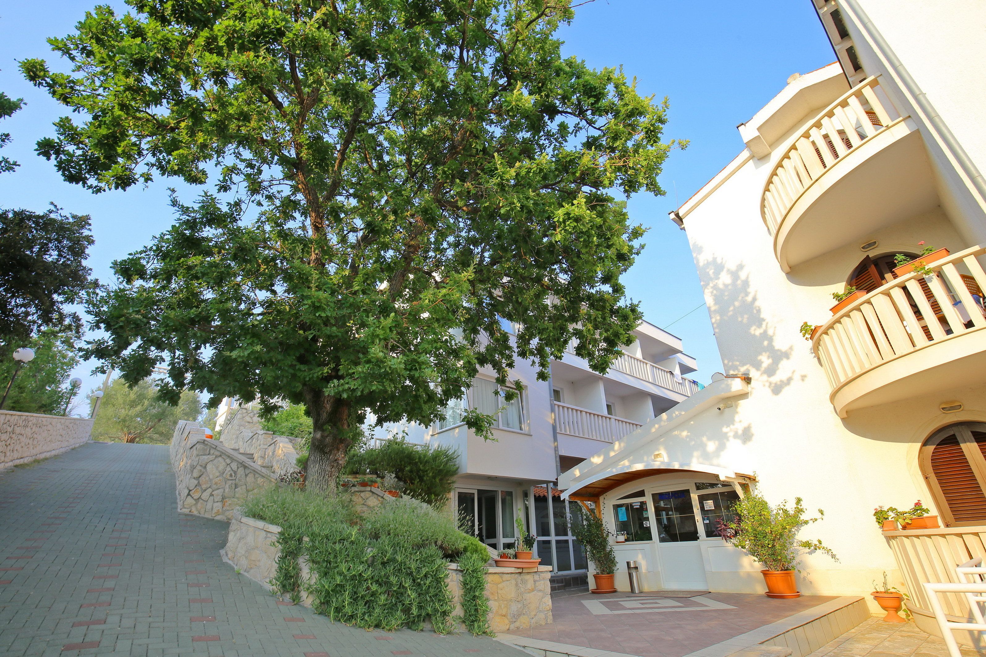 A building with a curved balcony, a stone wall, and potted plants.