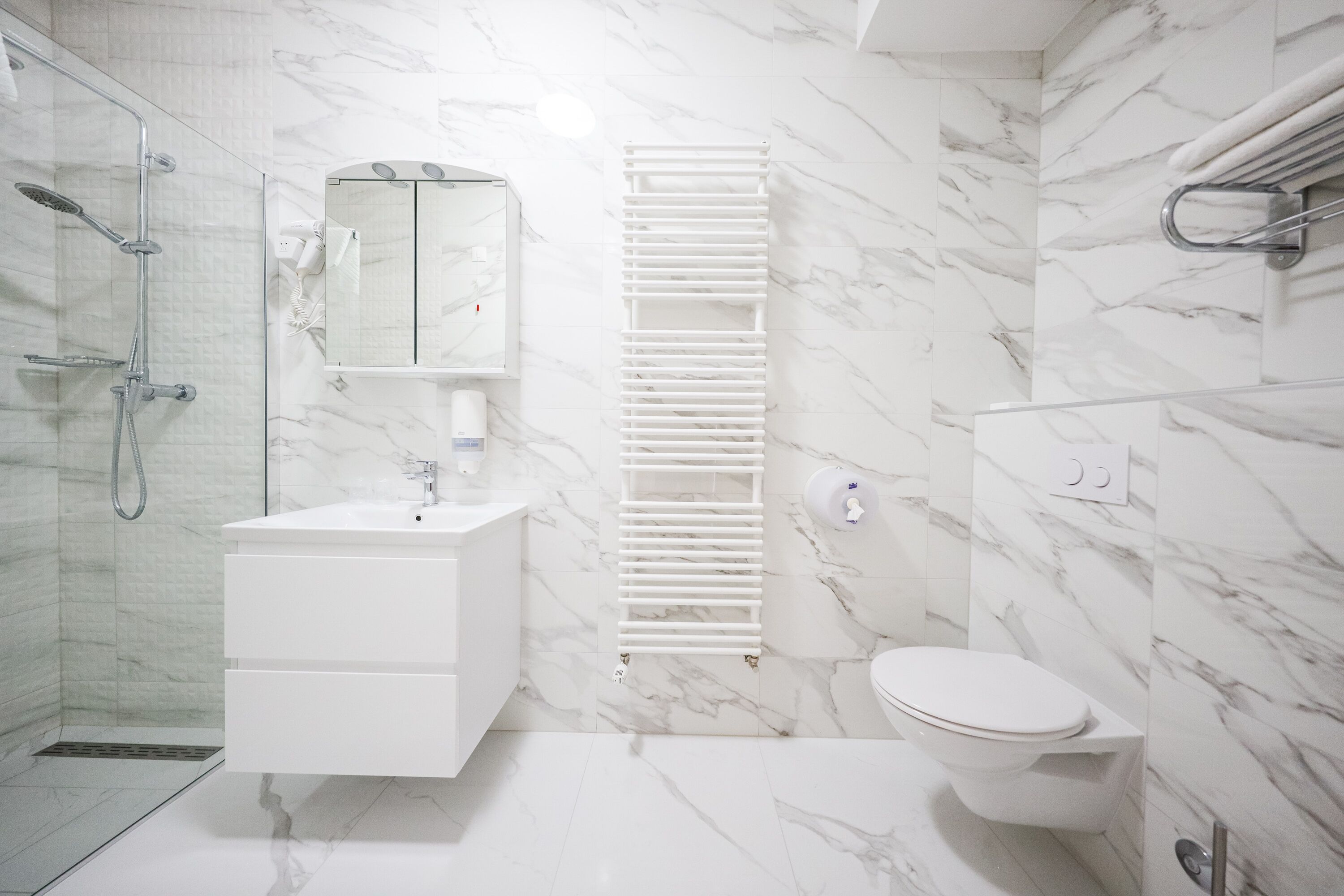 A modern bathroom with a glass-enclosed shower, a white vanity with a mirror, and a toilet with a towel rack.