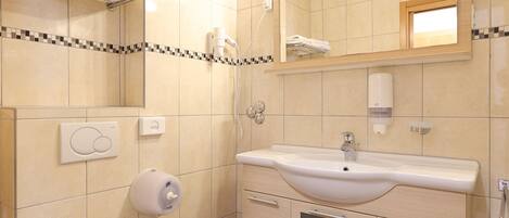 Un baño con inodoro, lavabo, espejo, toallero y zona de ducha.