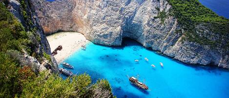 Un paisaje costero con una formación rocosa natural, una playa y aguas azules cristalinas.
