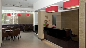 Un hall d’hôtel moderne avec un comptoir d’accueil, un espace salon et de grandes fenêtres.