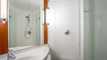 A bathroom with a white sink, a mirror, a shower, and a toilet.