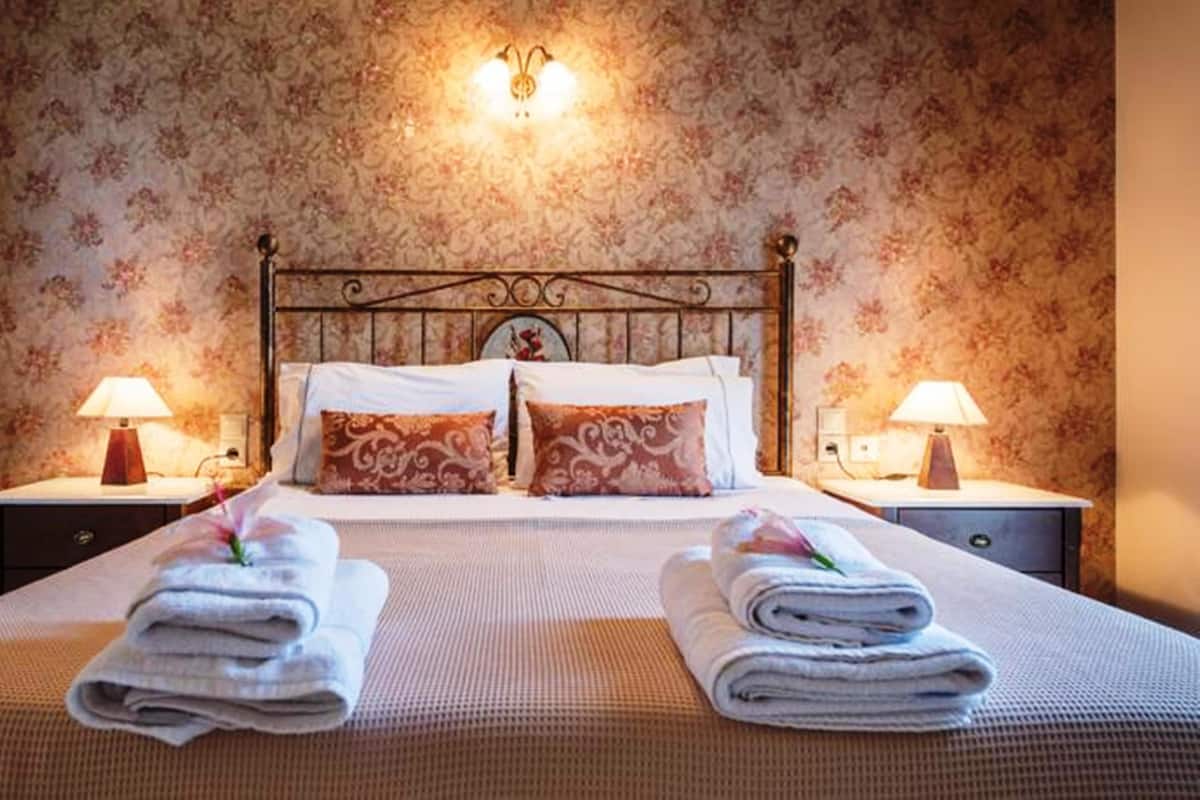 A neatly made bed with two pillows, a headboard, and two bedside tables with lamps.