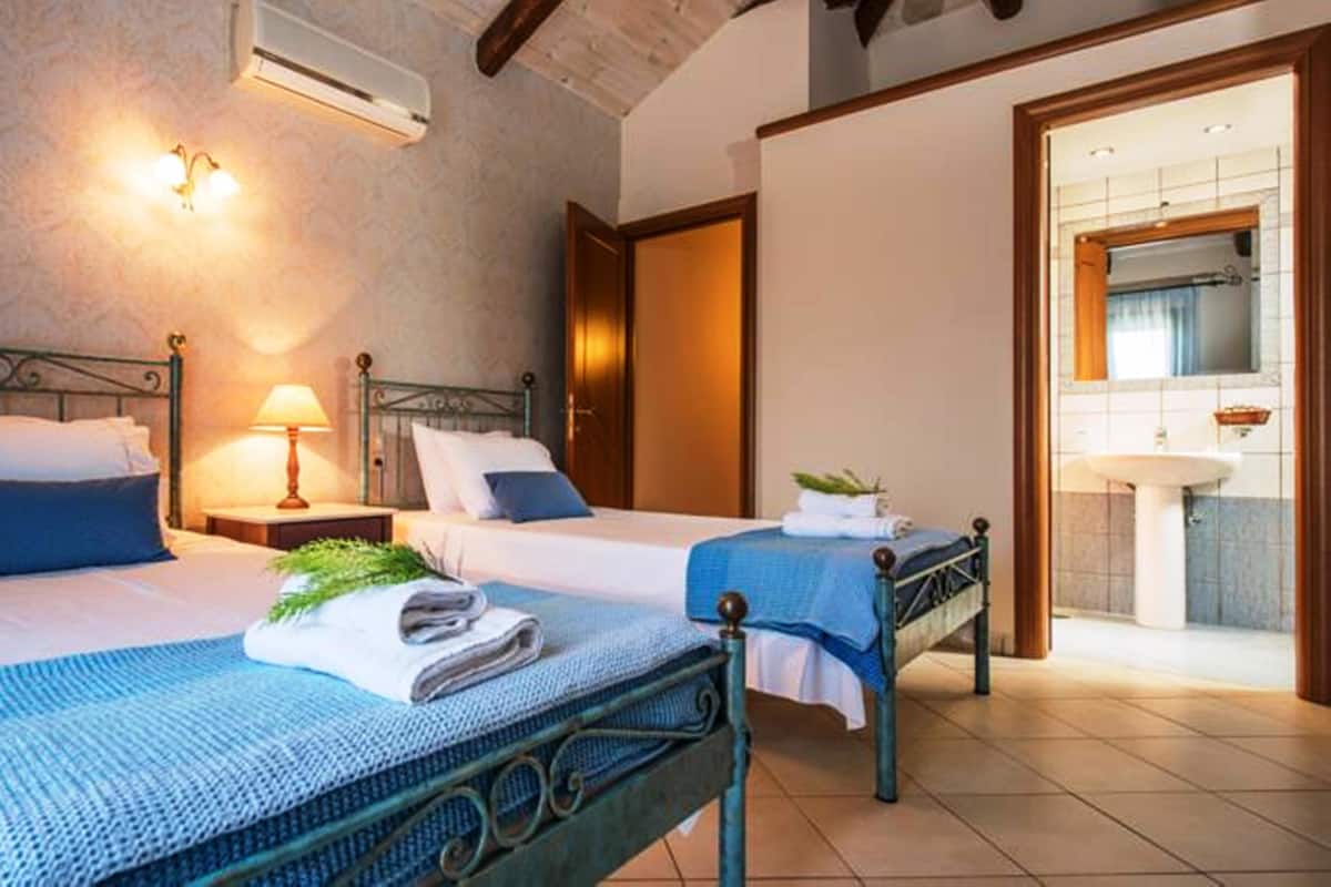 A hotel room with two beds, a bathroom, and a small sitting area.