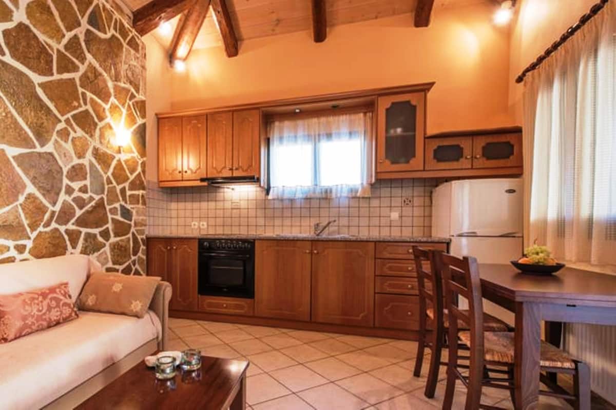 A cozy kitchen with stone walls, wooden cabinets, and a tiled floor.