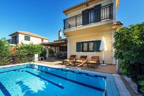A two-story building with a swimming pool, outdoor seating, and a balcony.