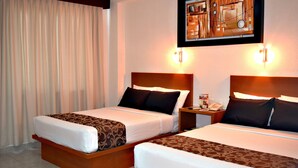 A hotel room with two beds, each with a wooden headboard, white bedding, and brown decorative pillows. There is a nightstand with a phone and a framed picture on the wall above the beds. - Best Western Global Express (Veracruz)