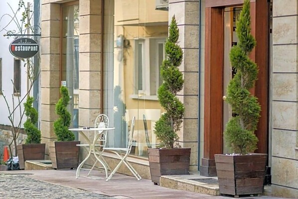 A restaurant with outdoor seating, including a table and chairs, and potted plants. - Studio (Veliko Tarnovo)