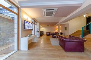 A spacious living area with a modern fireplace, a television mounted on the wall, and a staircase leading to an upper level. - Studio (Veliko Tarnovo)