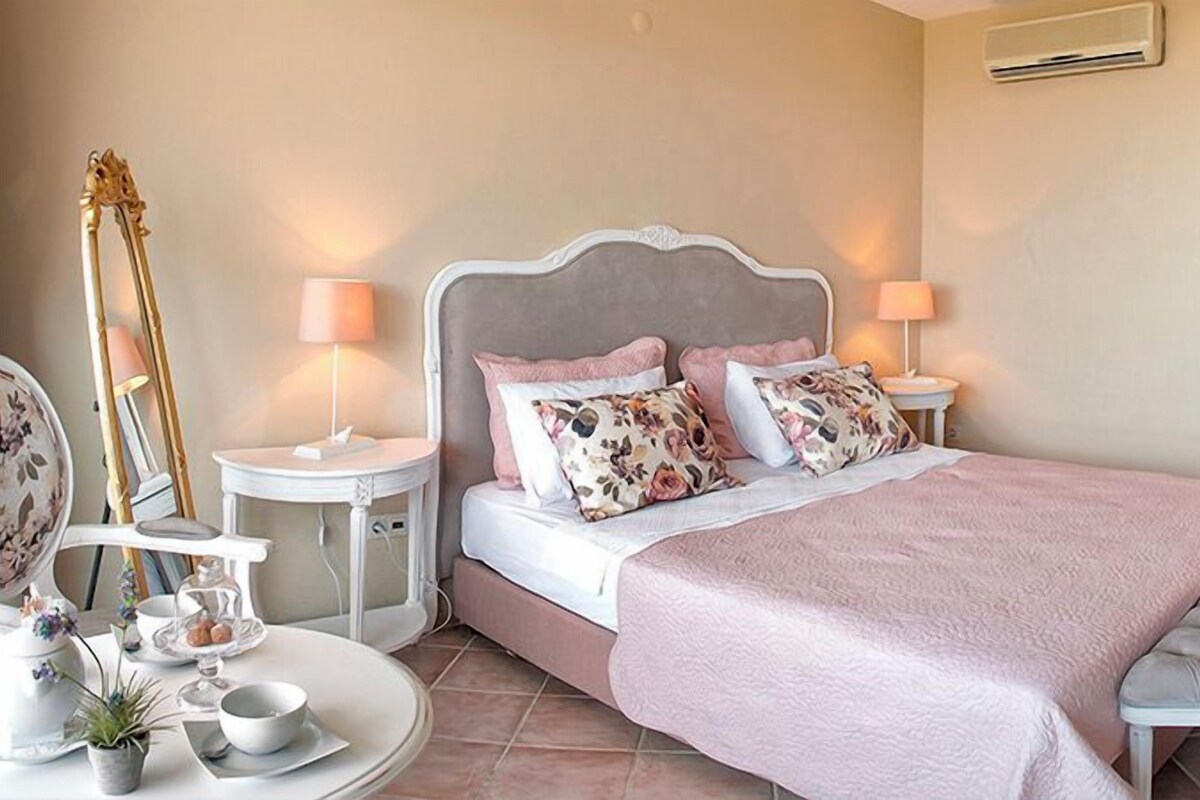 A bedroom with a bed, bedside tables, a mirror, and a lamp.