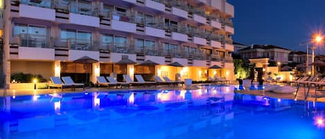 A hotel with a swimming pool, multiple balconies, and outdoor seating areas.