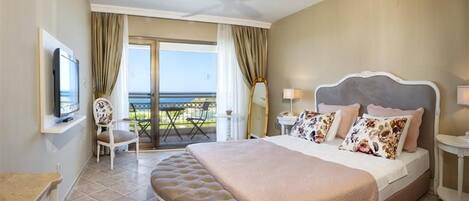 A hotel room with a large bed, a television, a balcony with a view, and a ceiling fan.