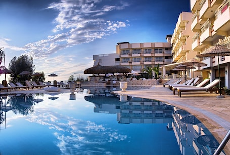 Una piscina al aire libre, sombrillas, sillones reclinables de piscina