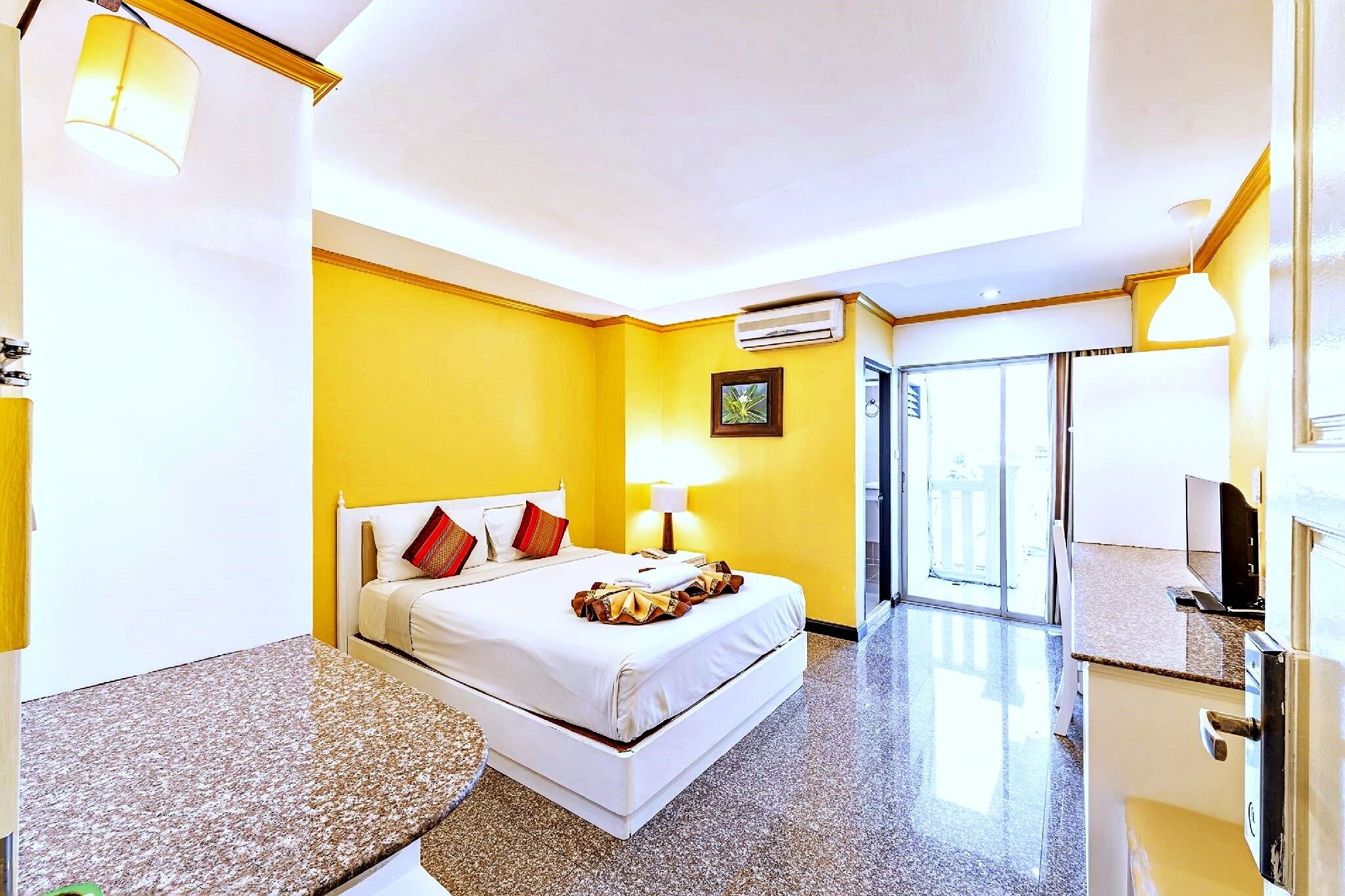 A hotel room with a bed, a bedside table, a lamp, and a window.