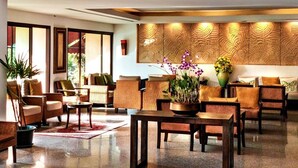 A spacious lobby with a reception desk, comfortable seating areas, and a decorative wall panel.