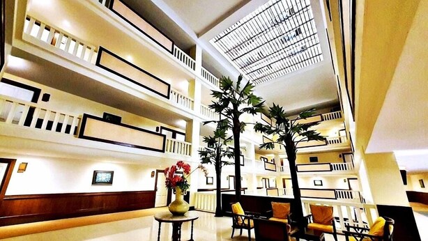 A spacious lobby with multiple floors, a central staircase, and a seating area with chairs and a table.