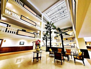 A spacious lobby with multiple floors, a central staircase, and a seating area with chairs and a table. - Royal Peninsula Hotel Chiang Mai (Chiang Mai)