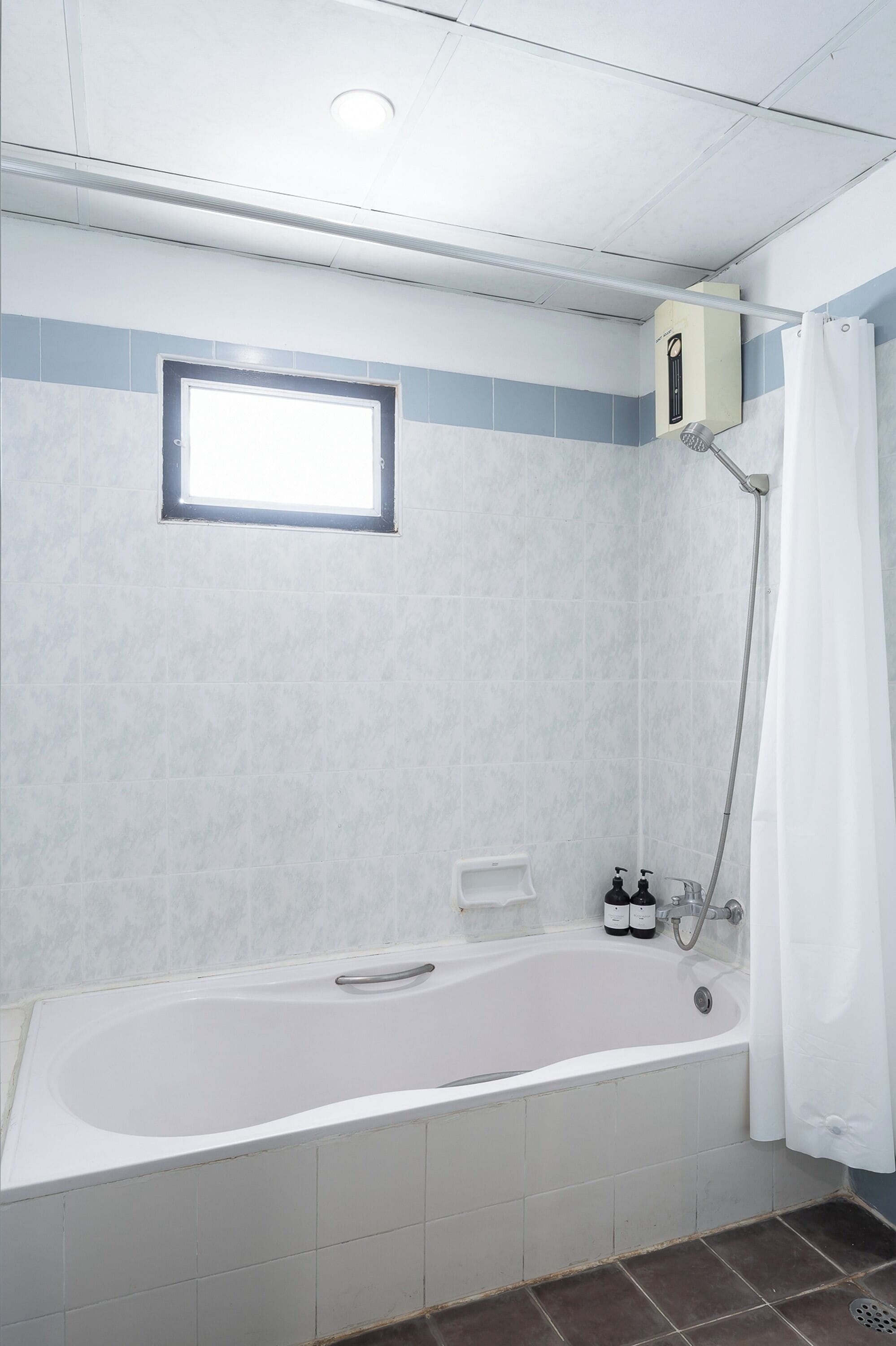 A bathroom with a bathtub, a shower, a window, and a towel rack.