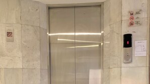 Un ascenseur doté d’un écran numérique, de murs en marbre et d’un sol à motifs.