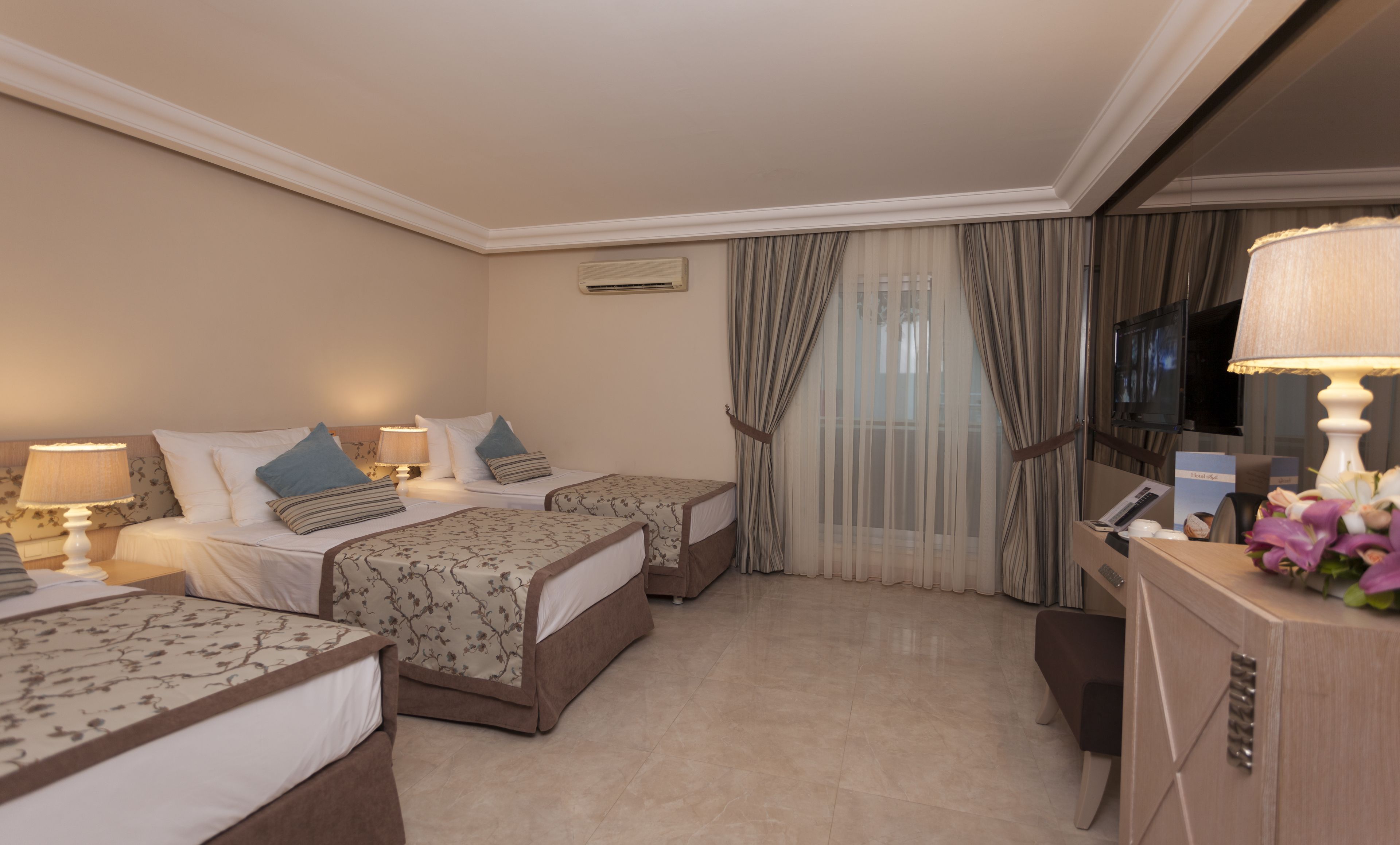 A hotel room with two beds, a desk, a TV, and a minibar.