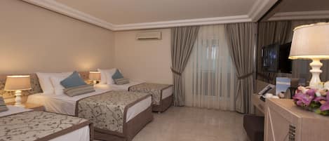 A hotel room with two beds, a desk, a TV, and a minibar.