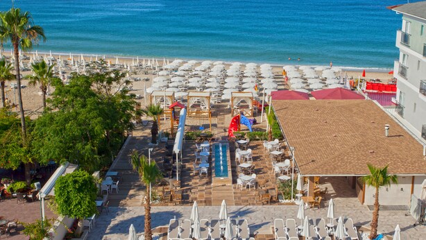 Een resort met een zwembad, ligbedden, parasols en uitzicht op de oceaan.