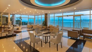 Eine moderne Lounge mit kreisförmigem Deckenstil, großen Fenstern mit Meerblick und unterschiedlichen Sitzmöglichkeiten.