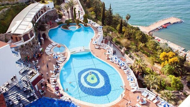Ein Resort mit zwei großen Schwimmbecken, einem Strandbereich und Meerblick.