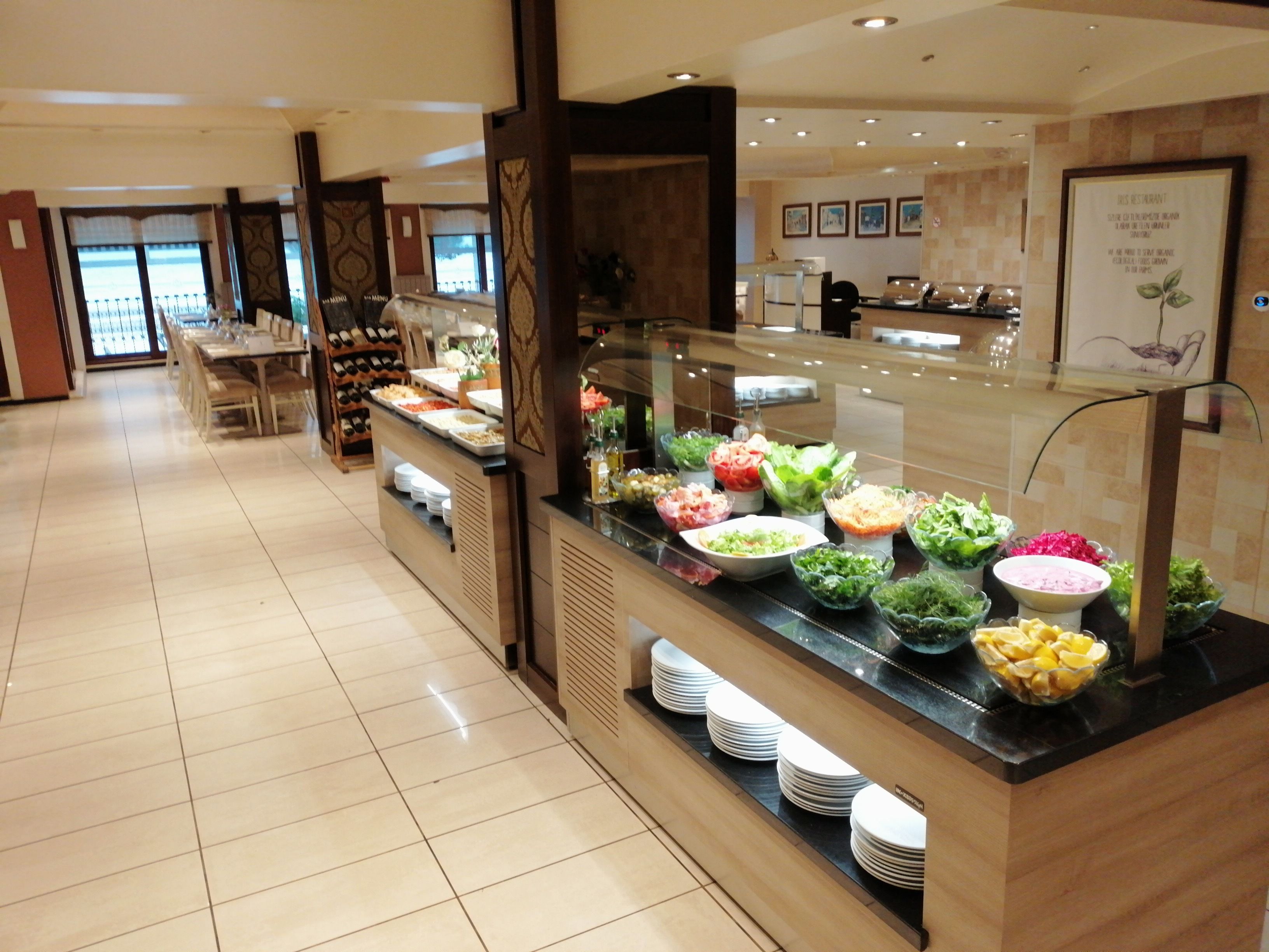 A buffet area with various food options, a wine rack, and a dining area in the background.