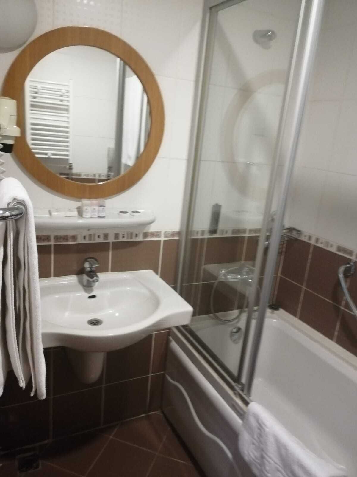 A bathroom with a sink, mirror, and shower.
