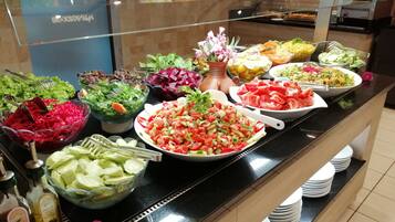 Een buffet met diverse salades, fruit en groenten.