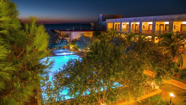 Un complexe hôtelier doté de plusieurs piscines, offrant une vue sur la plage et comprenant un bâtiment avec des balcons.