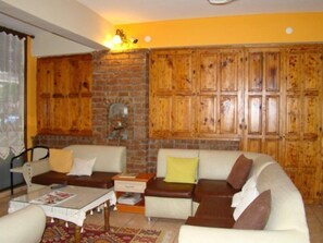 A living room with a brick wall, wooden cabinets, and a sofa set. - Ozcakil Hotel (Alanya)