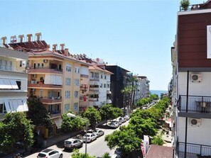 A row of multi-story residential buildings with balconies, parked cars, and trees along the street. - Ozcakil Hotel (Alanya)