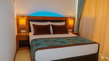 Una cama bien hecha con una colcha estampada con motivos florales, dos almohadas marrones y un cabecero de madera con lámparas fijadas a la pared.