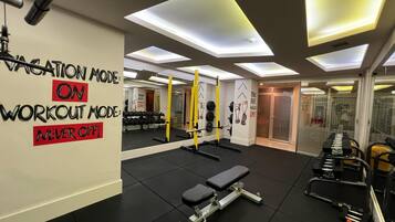Un gimnasio con piso de goma negra, equipamiento de levantamiento de pesas y arte motivacional en las paredes.