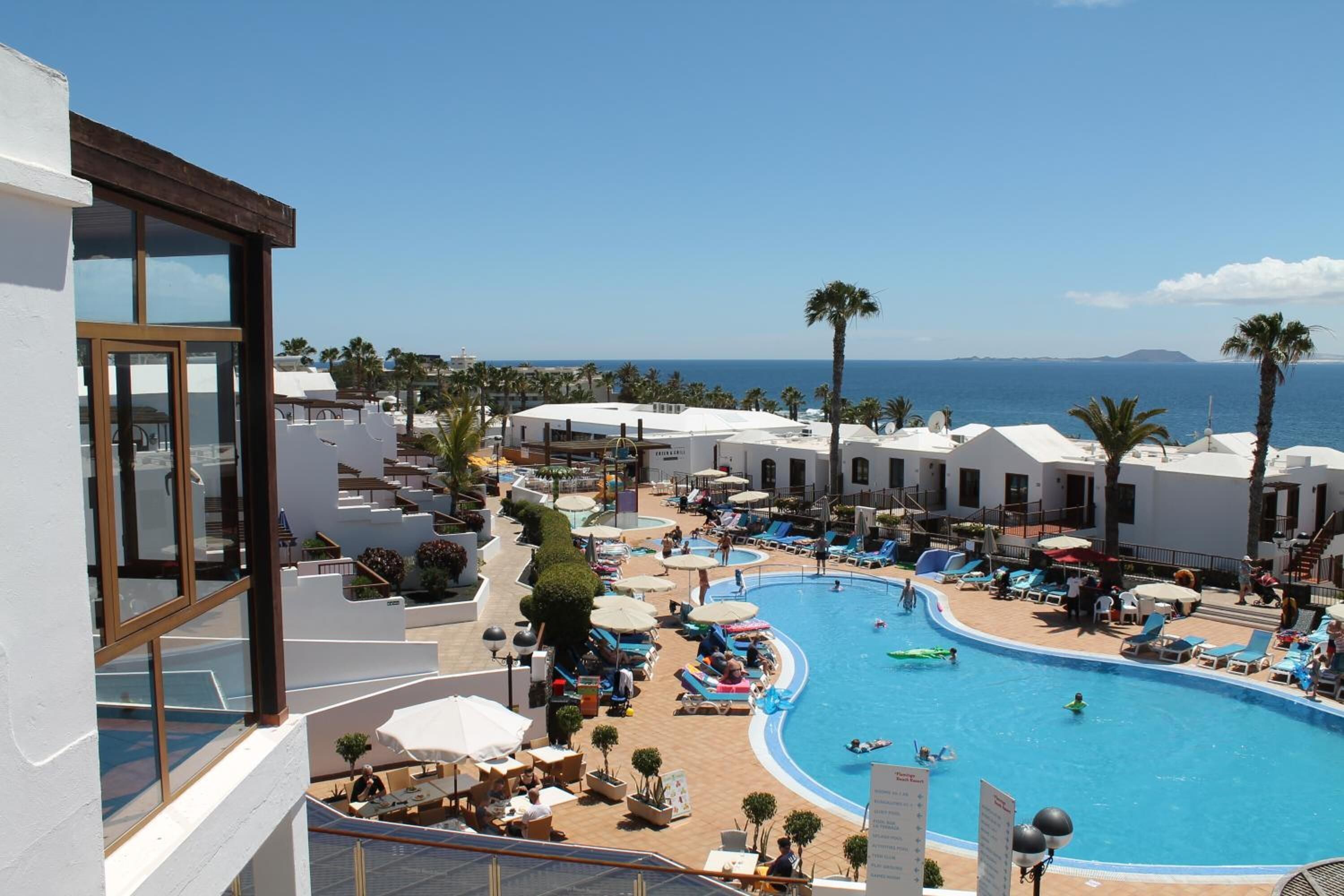 Un resort con una piscina grande, tumbonas y palmeras.
