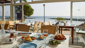 Comedor con mesas dispuestas para comidas, con vista panorámica al mar.